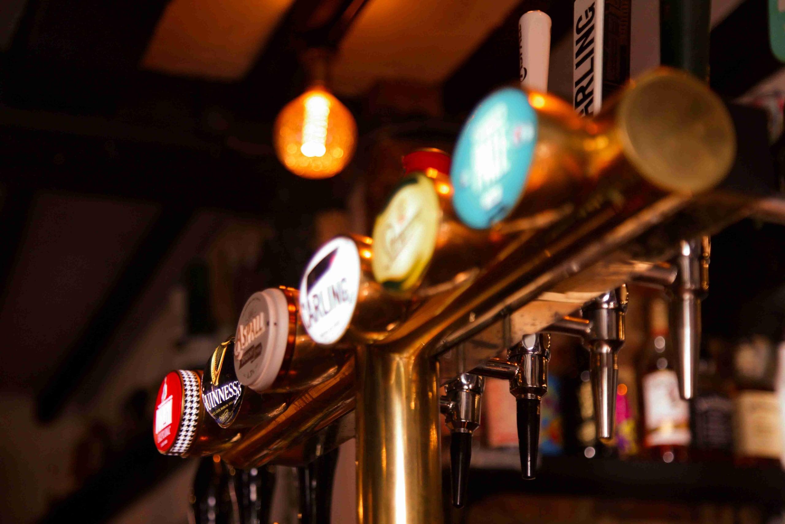 A closer look at the brass pump handles at the bar, backlit by the warm filament lamps behind.
