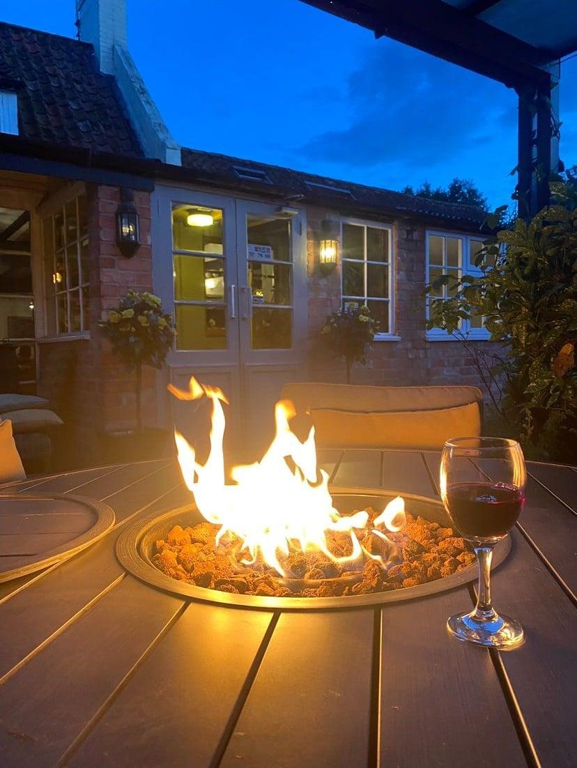 The pub's outdoor terrace at dusk with a lit firepit.