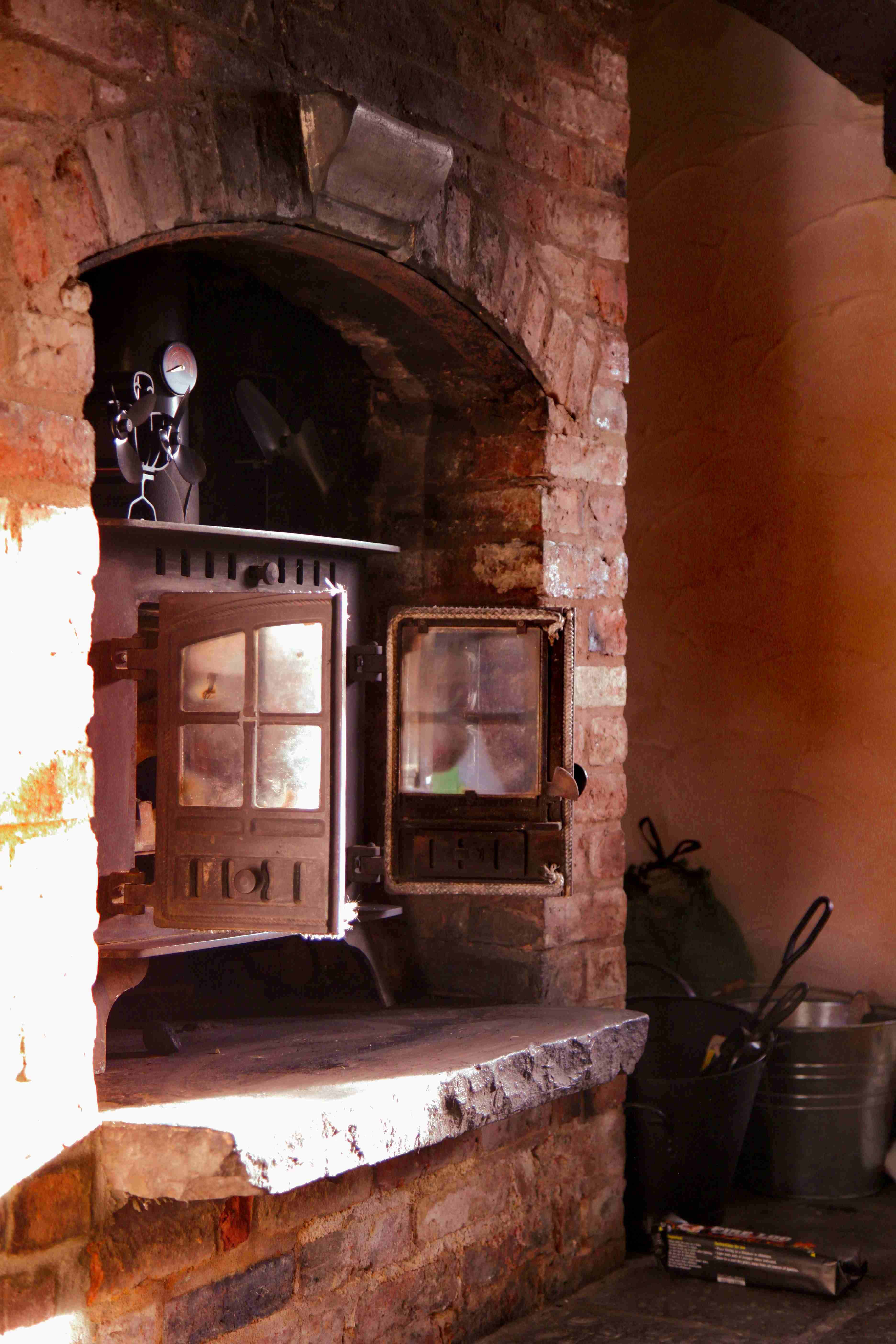 The pub's original brick fireplace with a cast-iron wood-burning stove and pressure gauge.